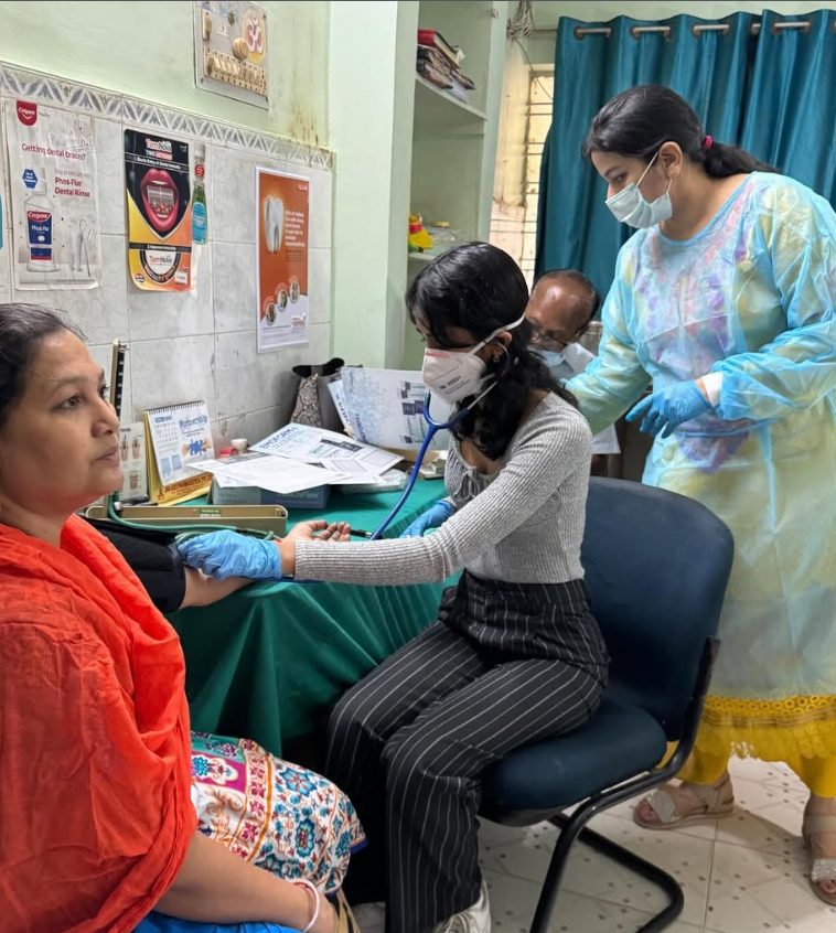 A WiseMed volunteer checking a patient's blood pressure at the dental camp in Patna